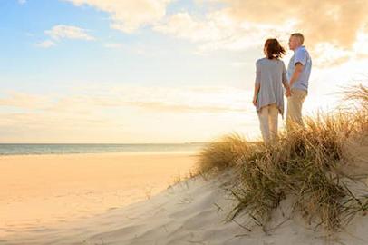 A younger couple on a beach, holding hands